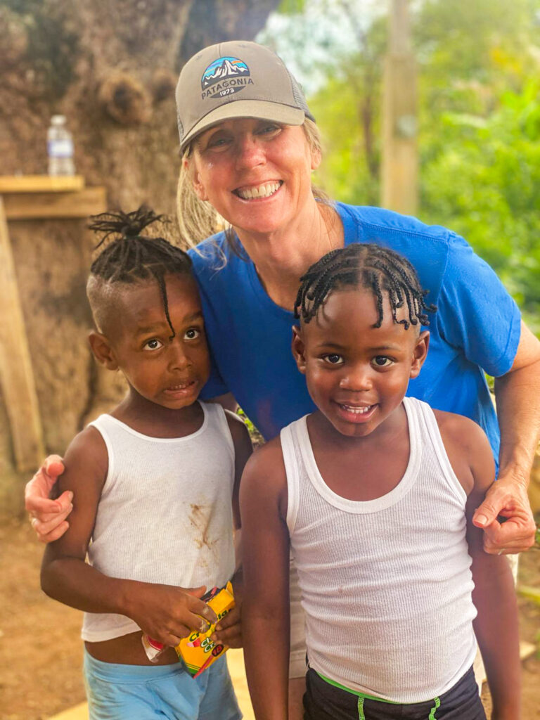 Volunteer woman smiling with two children outdoors.
