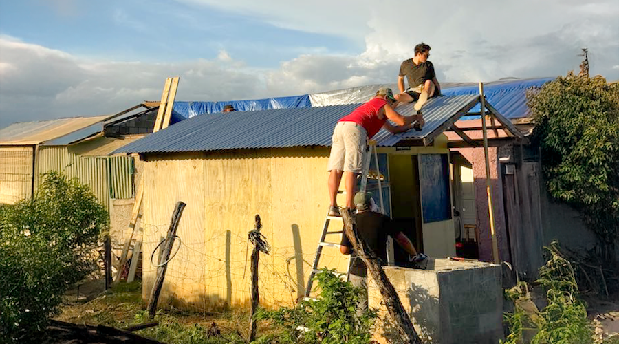 Two men working on roof of small house under construction.