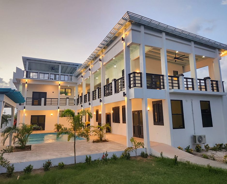 Modern two-story villa with balconies and palm trees.